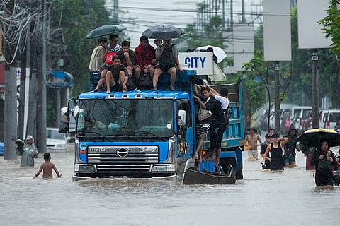 Philippines Tropical Storm Yagi: Commuters ride on top of a truck to avoid flood waters in Cainta